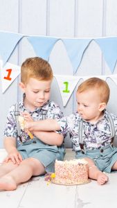 siblings sitting together at a cake smash photo shoot 2