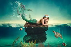 a little girl rests her head on her hands at a digital mermaid portrait photo shoot