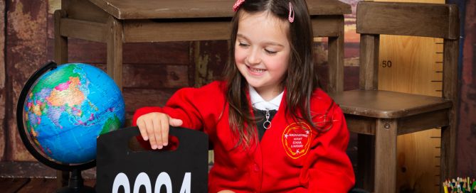 a little girl poses in her school uniform in a school themed set and she's looking at a sign that says 2024