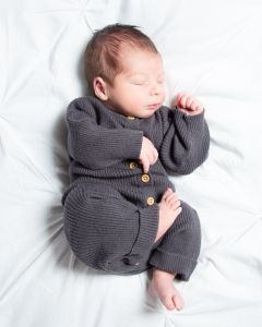 A newborn is sleeping on a duvet wearing a grey sleepsuit at a professional photoshoot at my studio in West Sussex