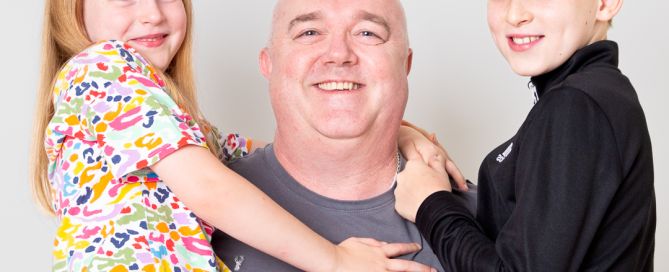 a dad holds his children one on each side in a family tradition at their studio visit