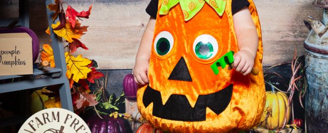 a little boy dressed in a pumpkin costume in a pumpkin themed set at a professional photo shoot