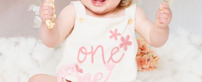 a little girl is happy with her cake at her first birthday photo shoot