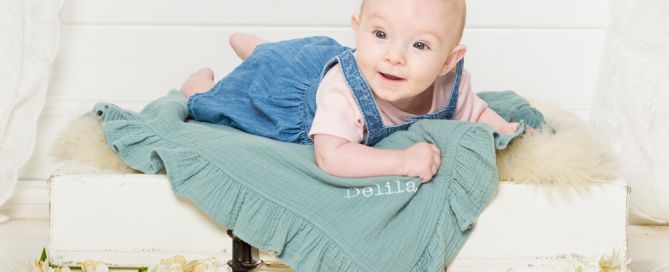 a baby on a vintage suitcase with cream flowers