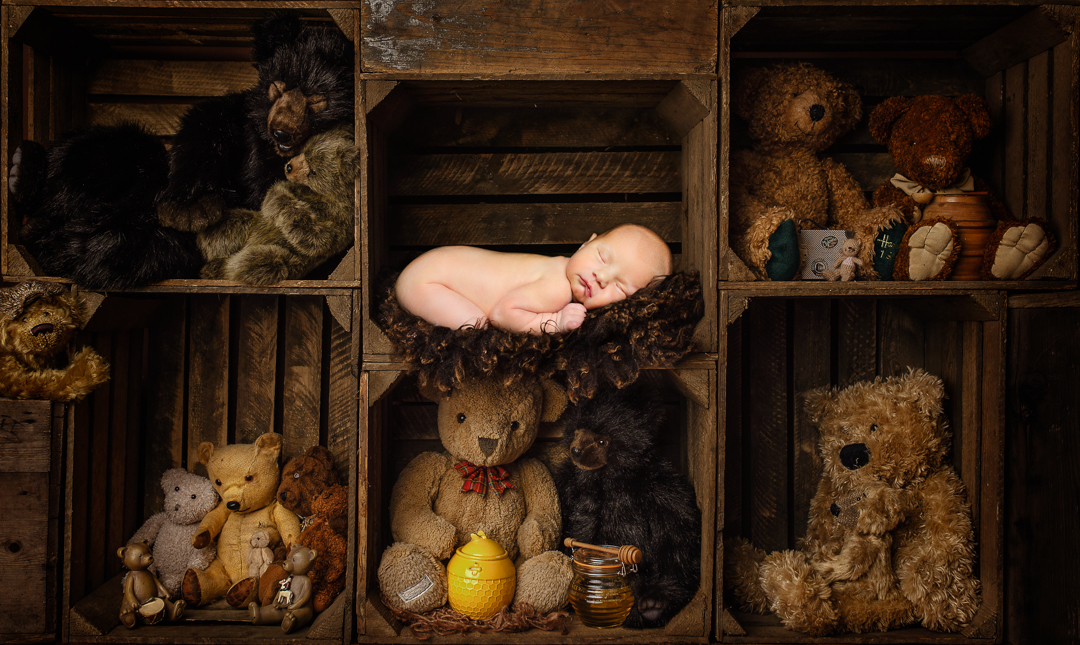 ANewborn Photography - Using Digital Backdrops a sleeping newborn against a backdrop of teddy bears stacked in crates