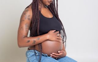 a pregnant woman kneels down looking at her baby bump at a professional photo shoot