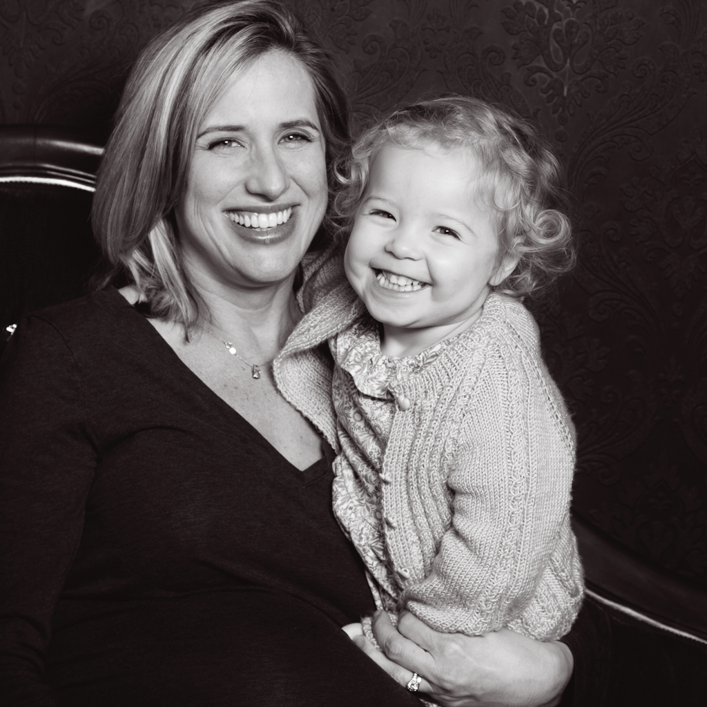 a black and white image of a mum and daughter both laughing and cuddled up at a professional photo shoot