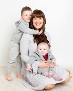 a mum poses with her two boys while sitting on the floor