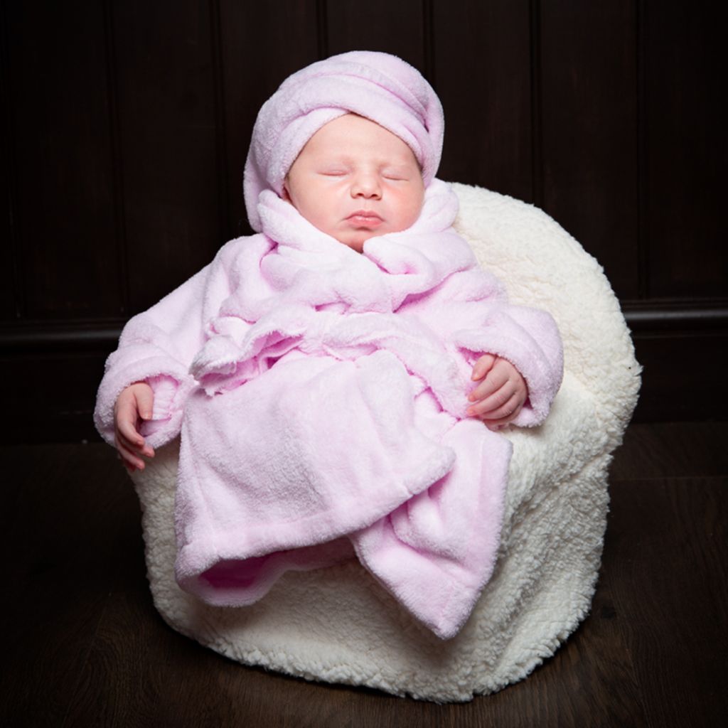 a newborn dressed in a pink robe and turban and fast asleep