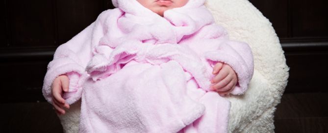 a newborn dressed in a pink robe and turban and fast asleep