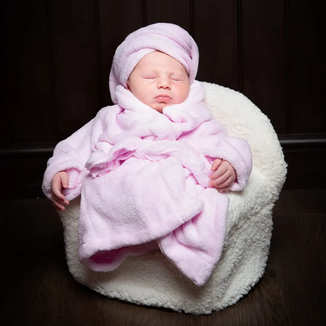a newborn dressed in a pink robe and turban and fast asleep