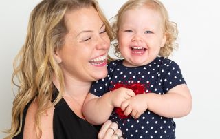 a mum poses with her baby girl and they're both laughing