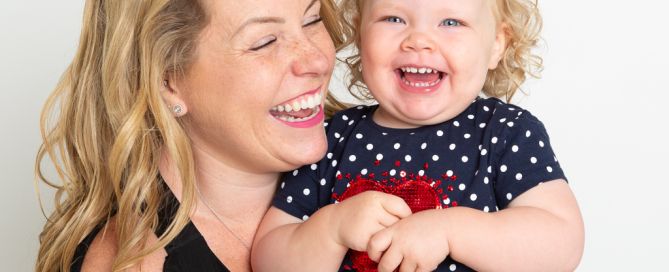 a mum poses with her baby girl and they're both laughing