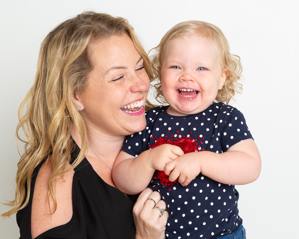 a mum poses with her baby girl and they're both laughing