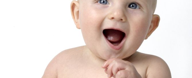 a little boy smiling for the camera against a white background
