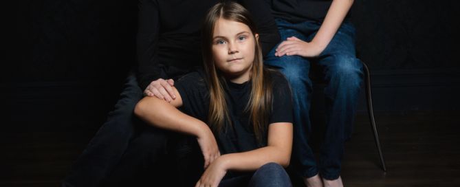 a family of two sisters and a brother pose in black shirts