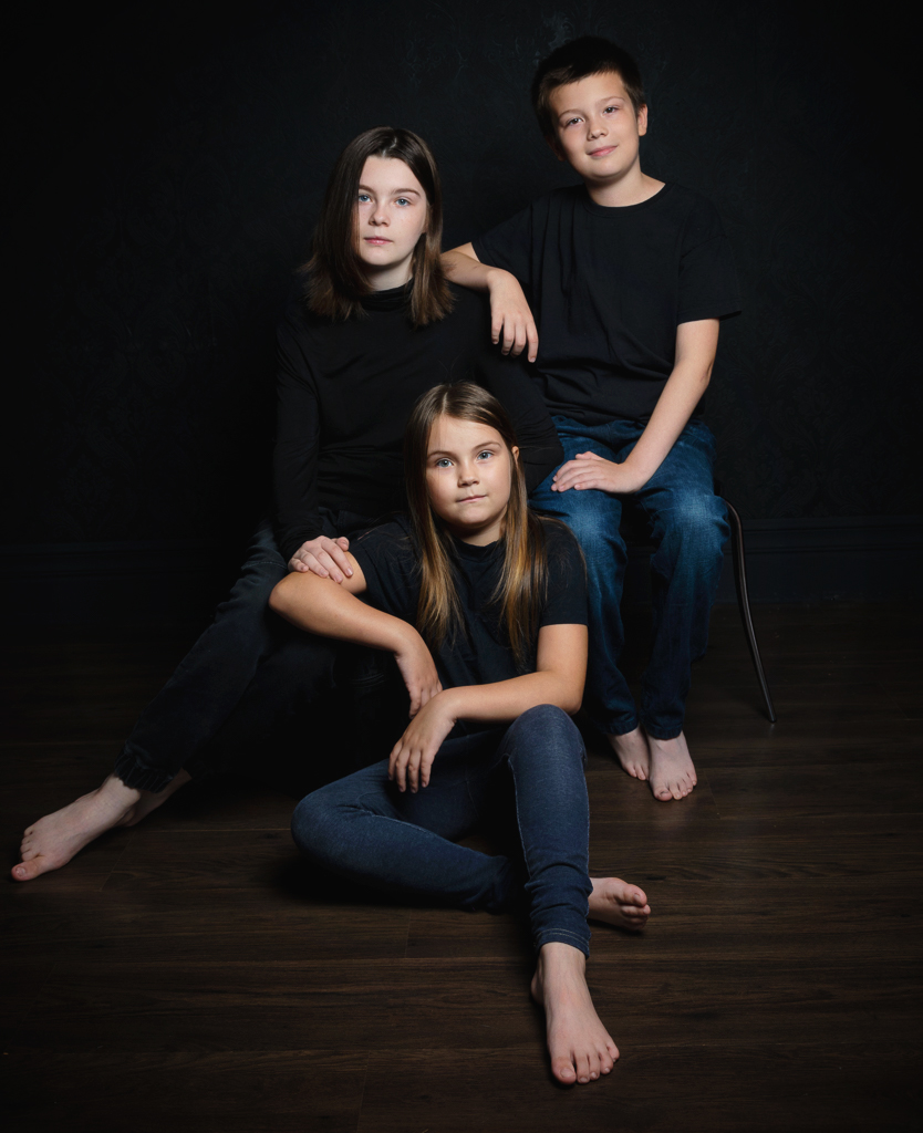 a family of two sisters and a brother pose in black shirts