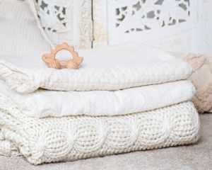 a stack of cream blankets with a wooden toy on top