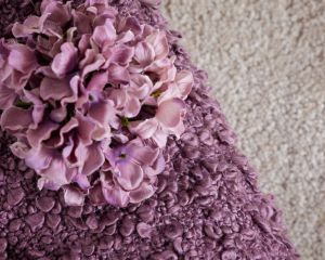 a lilac blanket with a flower on top of it