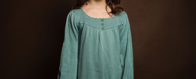 a dark haired girl poses in a blue dress against a brown backdrop for a fine art child's portrait