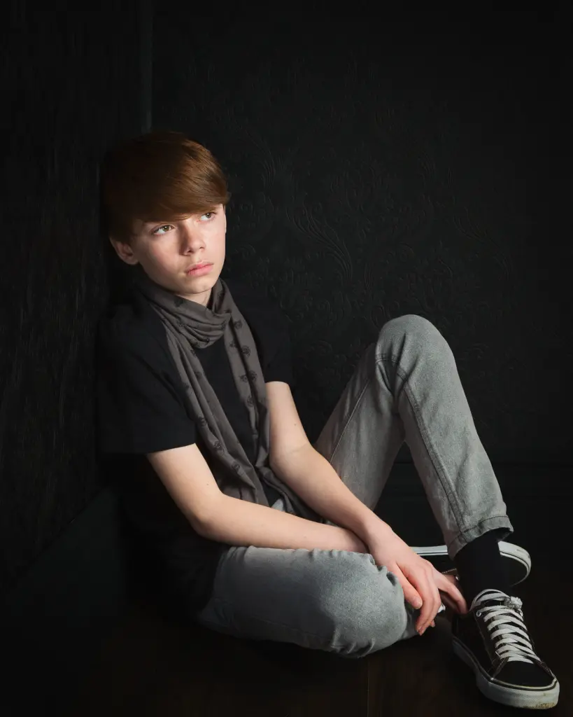 a boy poses for a fine art styled portrait in a studio