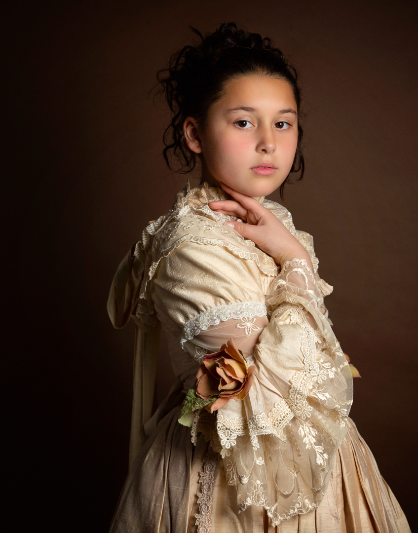 a girl poses in a lace vintage style dress for a fine art portrait