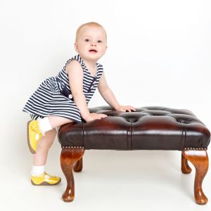 a baby in a dress and yellow boots poses for a professional photo
