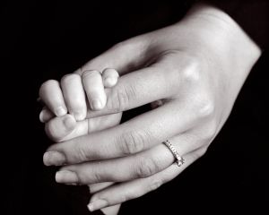 A newborn grips their mums finger - black and white image