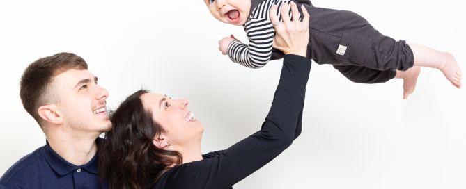 a mum and dad fly their son into the air at a portrait photo shoot