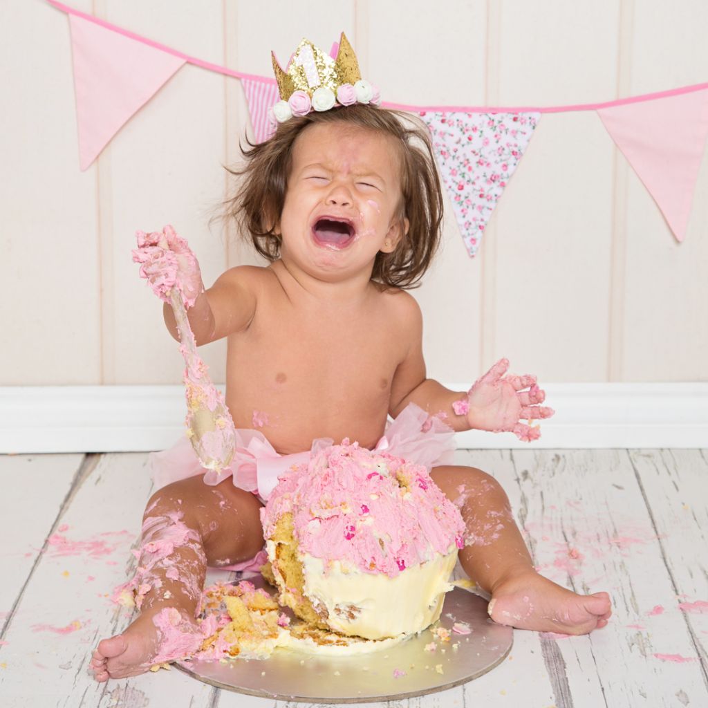 a little girl crying dramatically by her cake