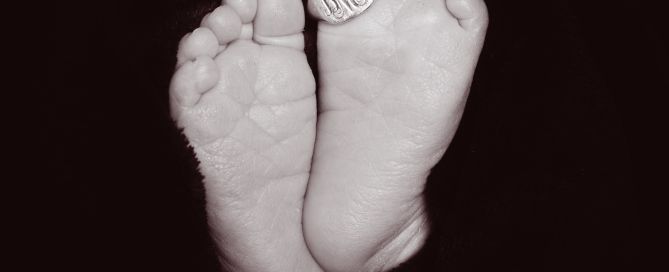 a pair of newborn feet with a signet ring on their toe