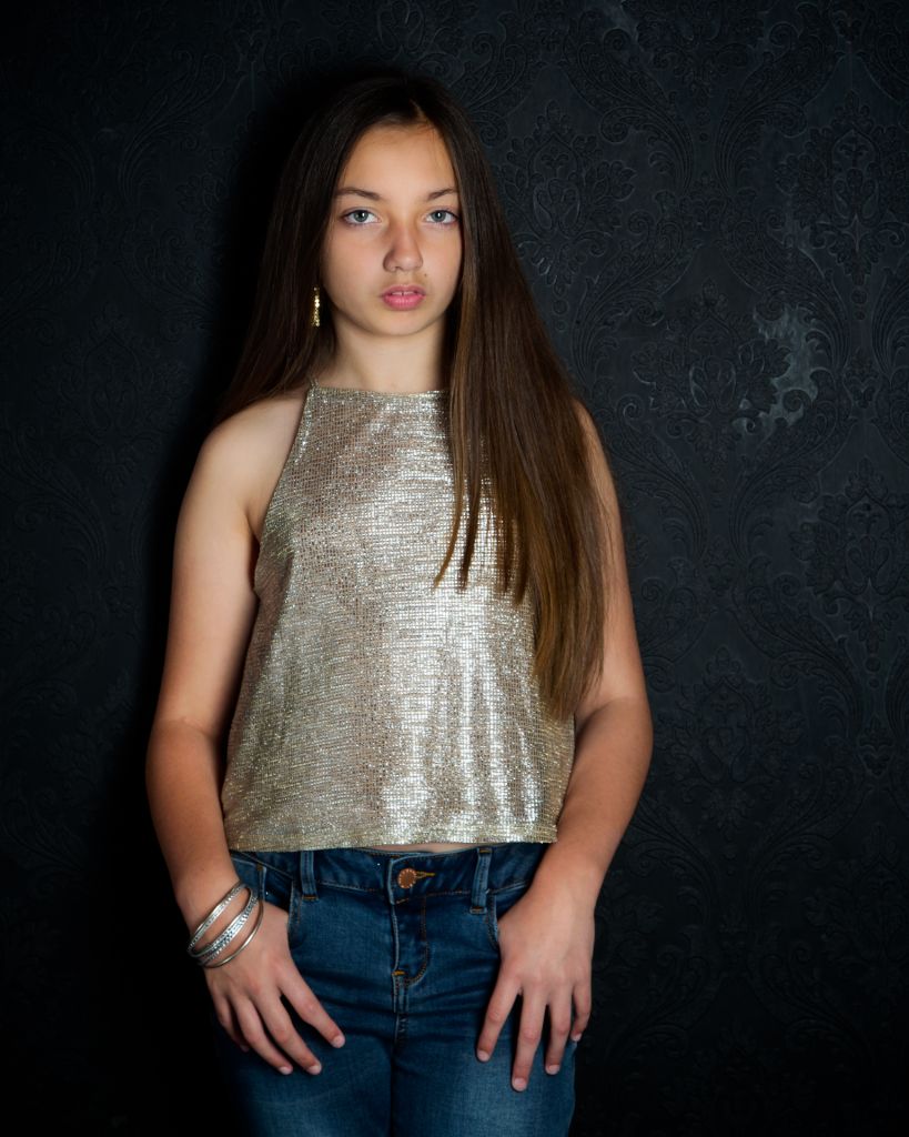 A fine art portrait of a child in a sparkly top and jeans