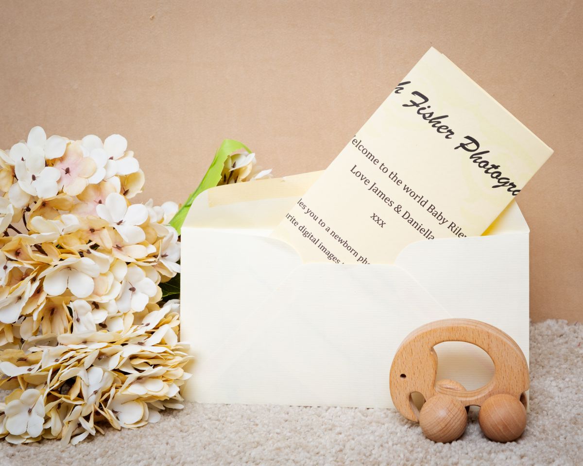A gift voucher for a photo shoot styled with cream flowers and a small toy