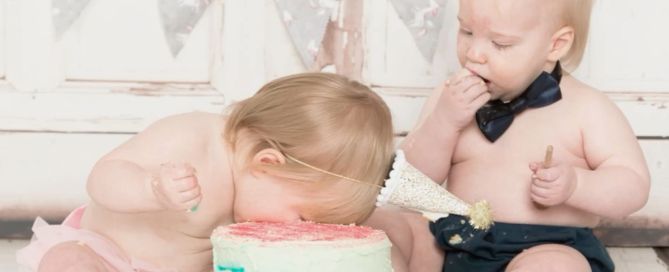 twins - the girl with her face buried in the cake and the boy taking a more cautious approach