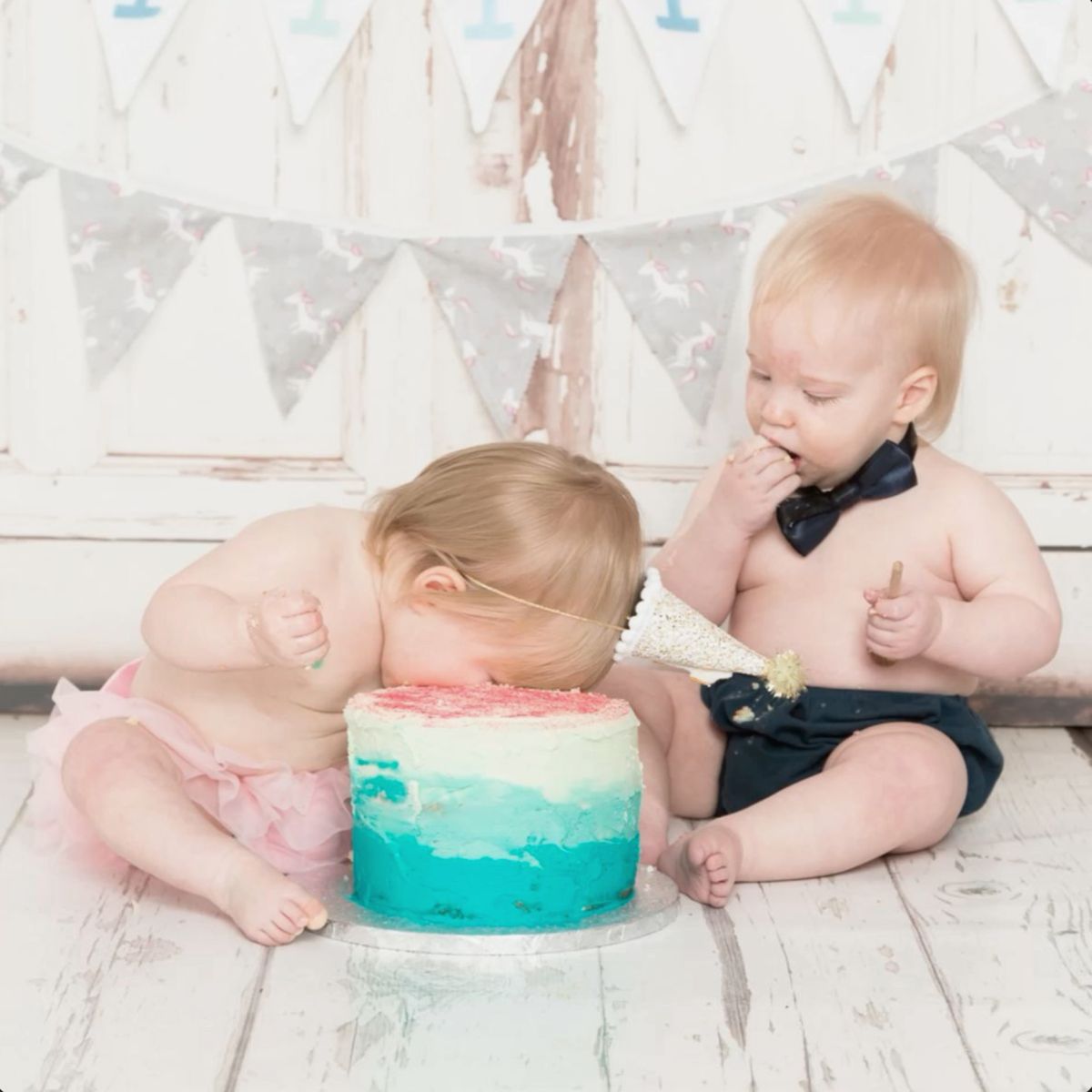 twins - the girl with her face buried in the cake and the boy taking a more cautious approach