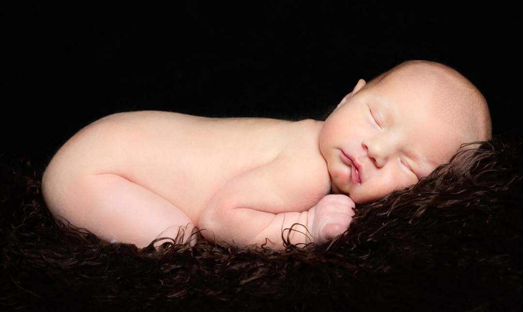 a newborn sleeping on a dark background for a digital composite