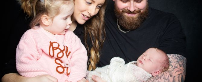 a mum, dad and older daughter welcome a newborn into their family at a professional photo shoot