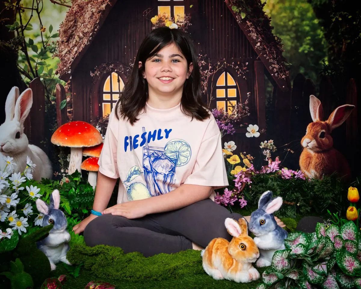 a girl sits with some fluffy bunnies at an easter mini shoot