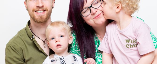 A little boy unexpectedly giving his mum a kiss in a family portrait shoot