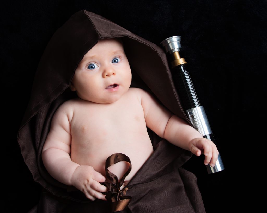 Baby Photography East Grinstead West Sussex A baby wrapped in a Jedi robe with a lightsaber