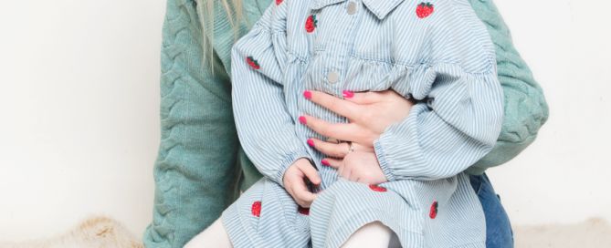 a little girl sits on her mums lap at a professional photo shoot