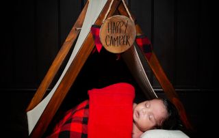 A newborn baby sleeps under a miniature camping tent