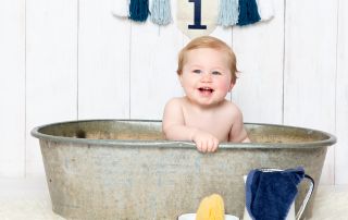 a little boy sits in a tin tub with white and blue enamel props