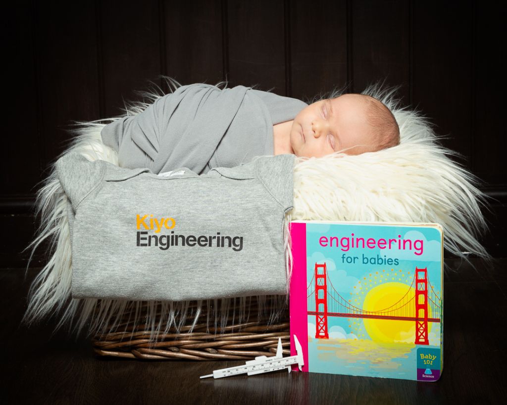 a baby wrapped in a swaddle sleeps in a basket with a book called engineering for babies