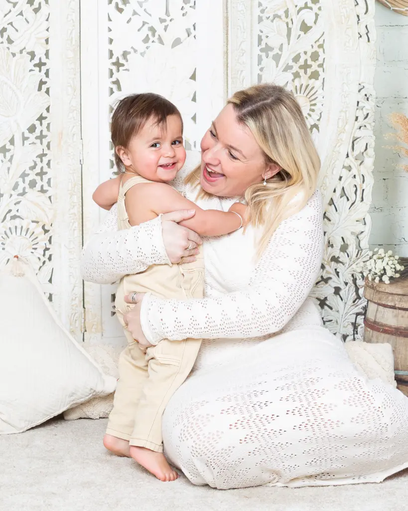 Family Photography East Grinstead A little boy smiles for the camera as he's getting a big hug from his mum