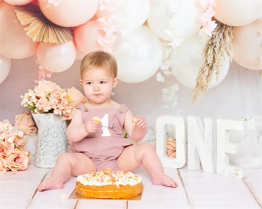 A little girl looks disappovingly off camera at her cake smash photo shoot