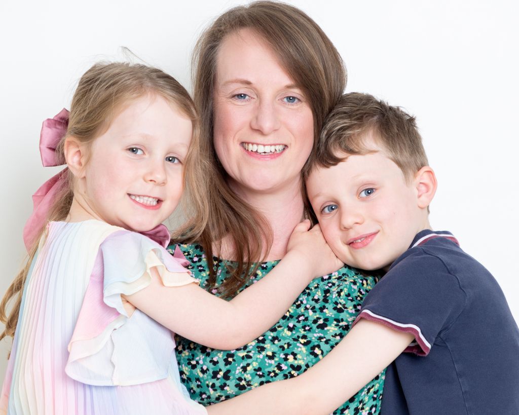 A mother smiles for the camera while holding both her children