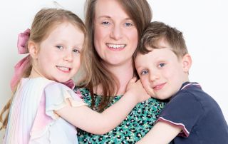 A mother smiles for the camera while holding both her children