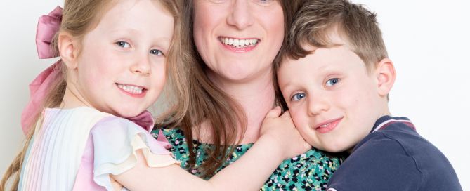 A mother smiles for the camera while holding both her children
