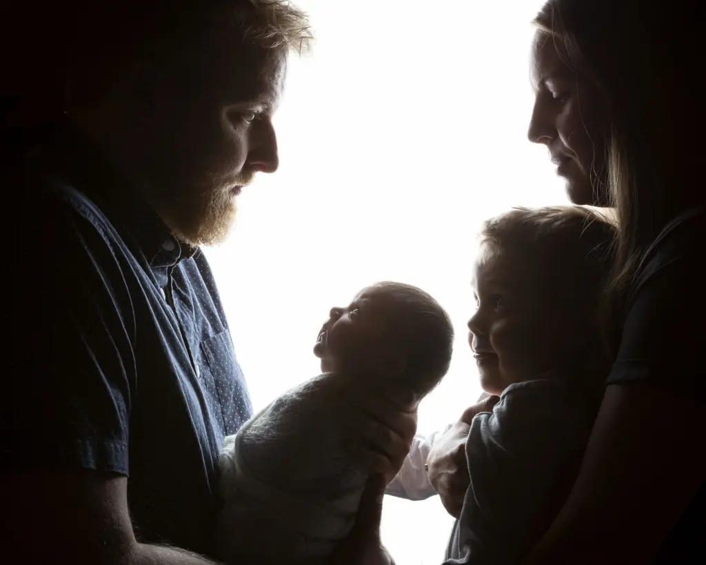 a silhouette of a family with mum, dad, newborn and big brother